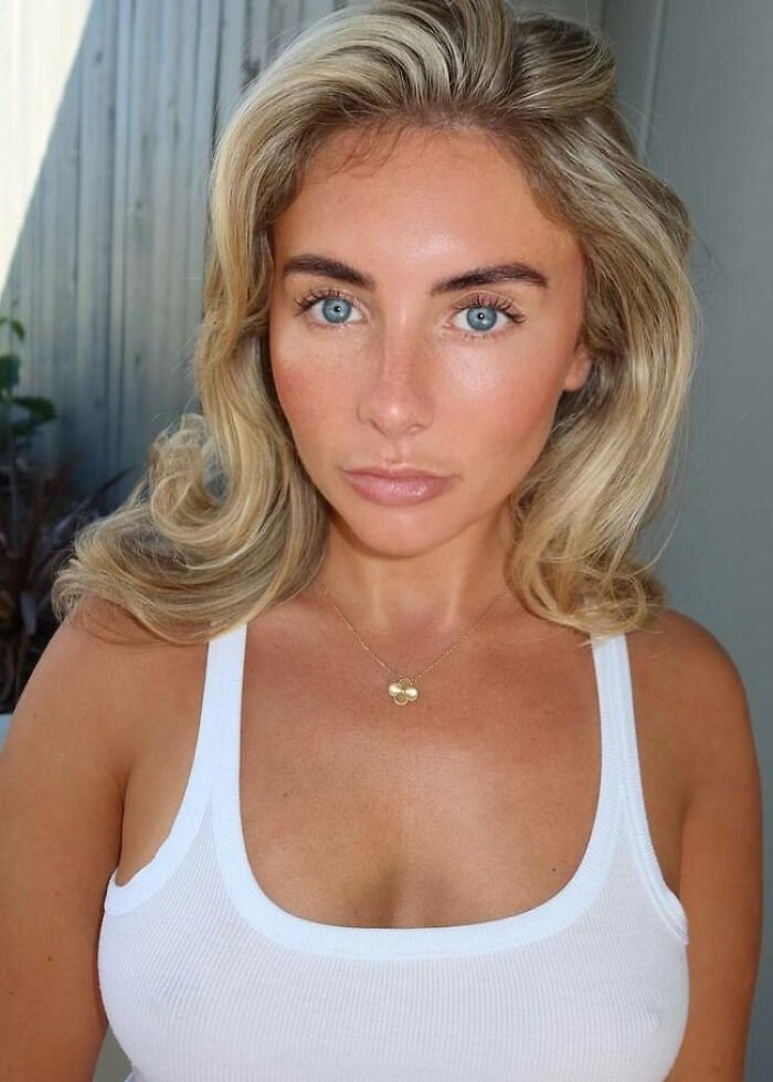 Participant from Bonnie Blue’s 400-Men Challenge with blonde hair and blue eyes wearing a white tank top indoors.