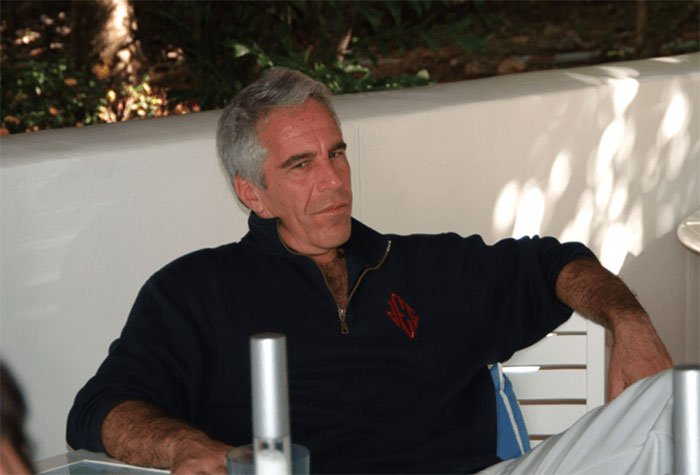Man sitting casually outdoors, relating to Stephen Hawking family's explanation for raunchy pics in Epstein files.