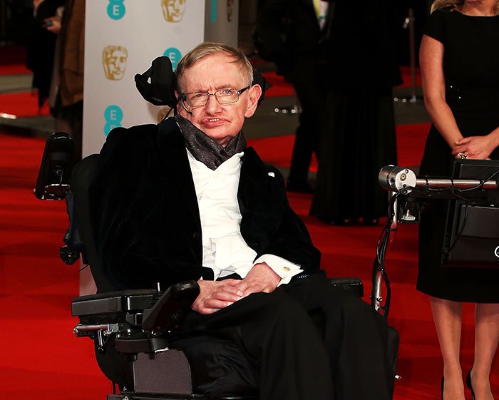 Stephen Hawking at a red carpet event, dressed formally, as family addresses Epstein files photo reactions.
