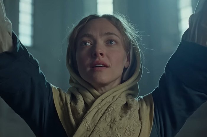 Amanda Seyfried wearing a prosthetic in a graphic scene from her recent film with a distressed expression and raised arms.