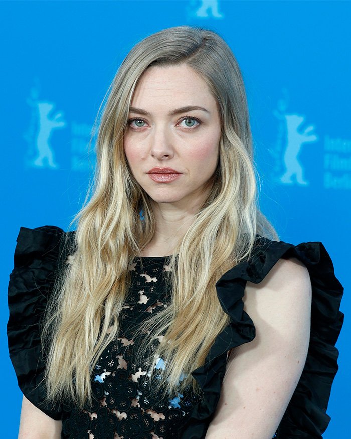 Amanda Seyfried posing at film festival event, wearing black lace top, discussing bizarre prosthetic for graphic movie scene.