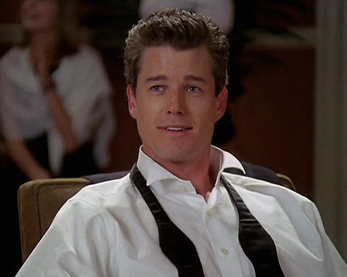 Eric Dane in a white shirt and undone black tie, portraying scandalous lifestyle and downward spiral in a dramatic scene.