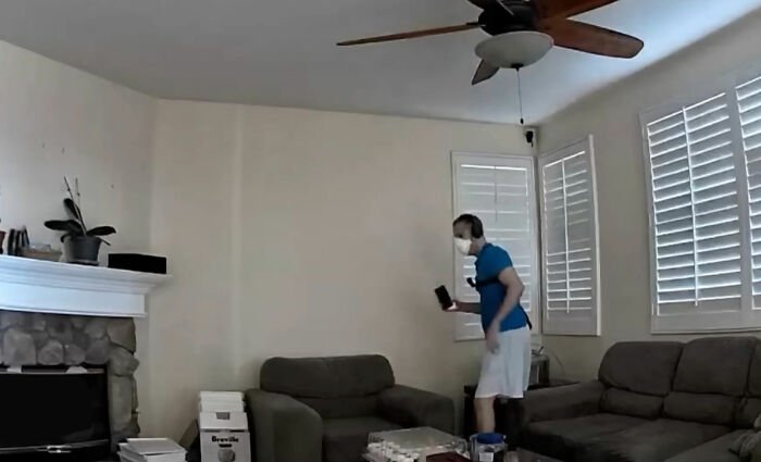 Man wearing mask standing in living room captured on security footage in a couple's home after multiple ER visits.