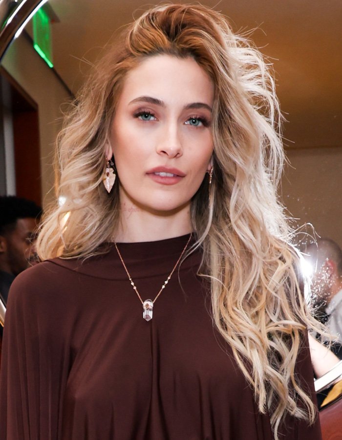 Paris Jackson with long blonde hair and a brown top, facing the camera amid fan scrutiny about her biological dad.