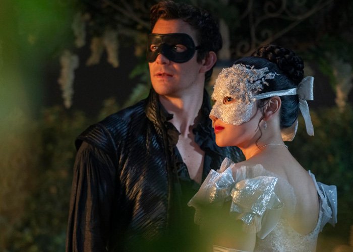Bridgerton star and co-actor wearing masks at a masquerade event, scene filled with mystery and elegance.