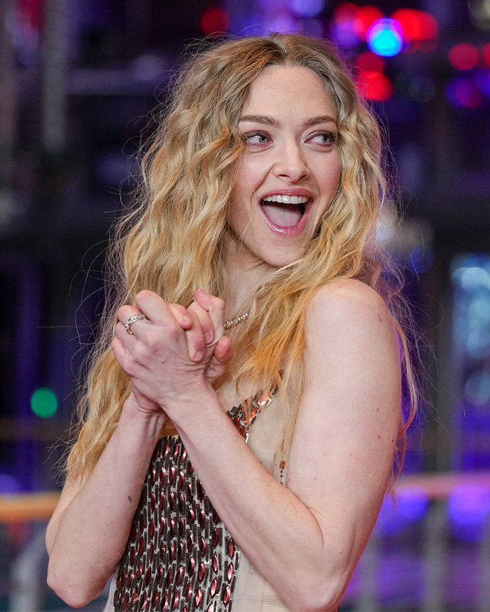 Amanda Seyfried smiling and clapping, revealing details of the bizarre prosthetic she wore for a graphic film scene