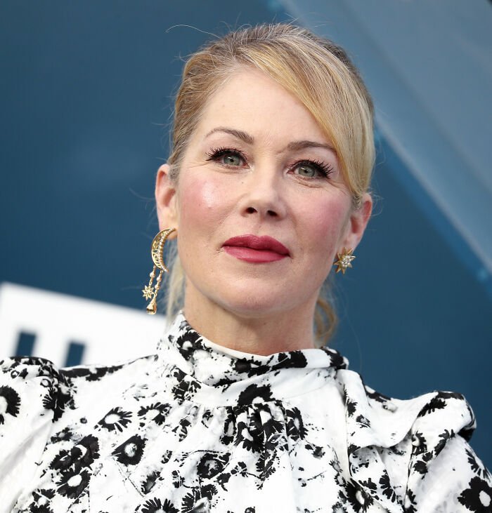 Christina Applegate wearing earrings and a floral dress, sharing a heartfelt update on her multiple sclerosis battle.