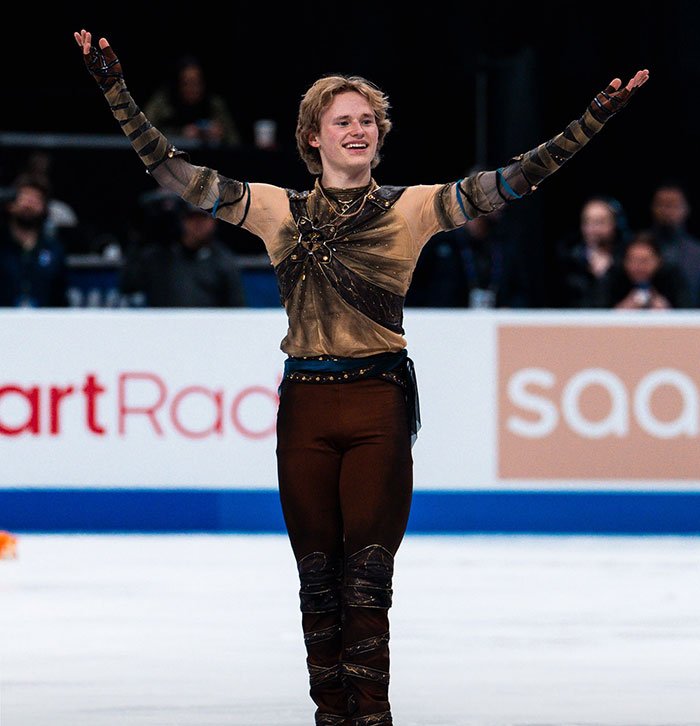 Olympic star Ilia Malinin on ice raising arms, with concern after fans spot troubling posts in his profile.