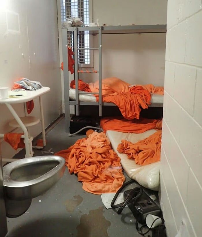Prison cell with messy orange blankets and metal bed, related to doctor at Jeffrey Epstein's post mortem claims.