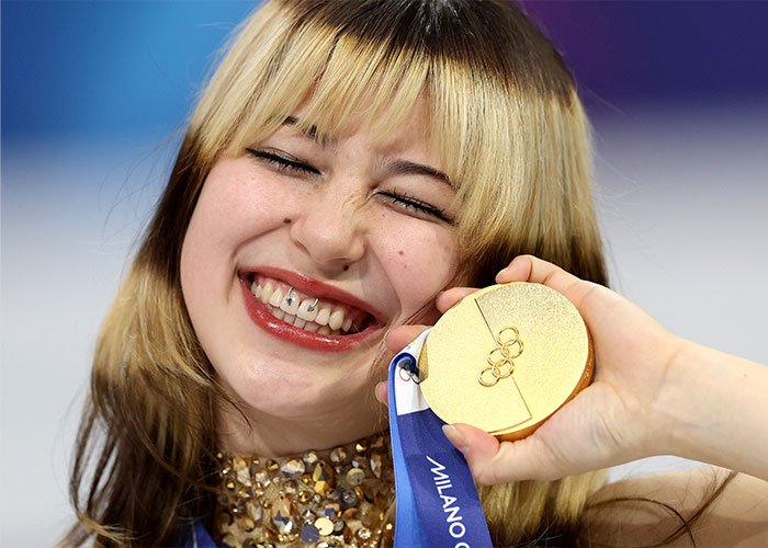 Close-up of a smiling young woman holding a gold medal, highlighting health experts warning about Alysa Liu’s viral look.