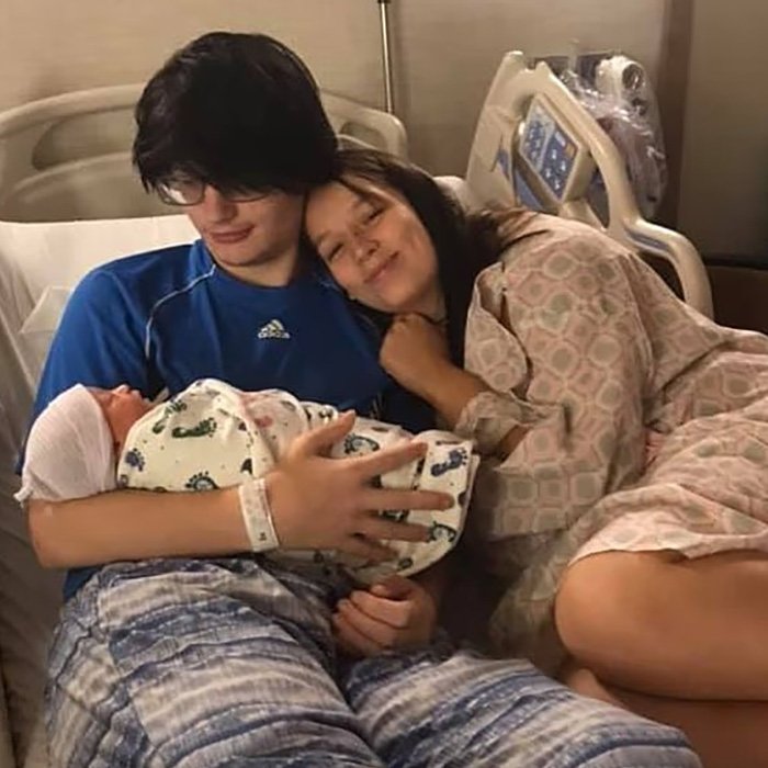 Young parents holding newborn baby girl in hospital bed, capturing a tender family moment after tragic passing.