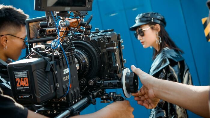 Film crew operating a professional camera while filming a scene, focusing on identifying films by closing scenes.