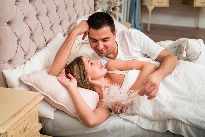 Couple lying in bed together, illustrating relationship issues and therapy for cheating husband concerns.