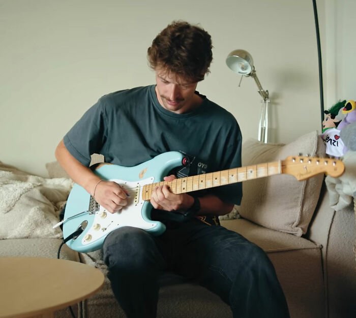 Young man playing electric guitar indoors, reflecting the emotional pain of Olympian cheating scandal public reaction.