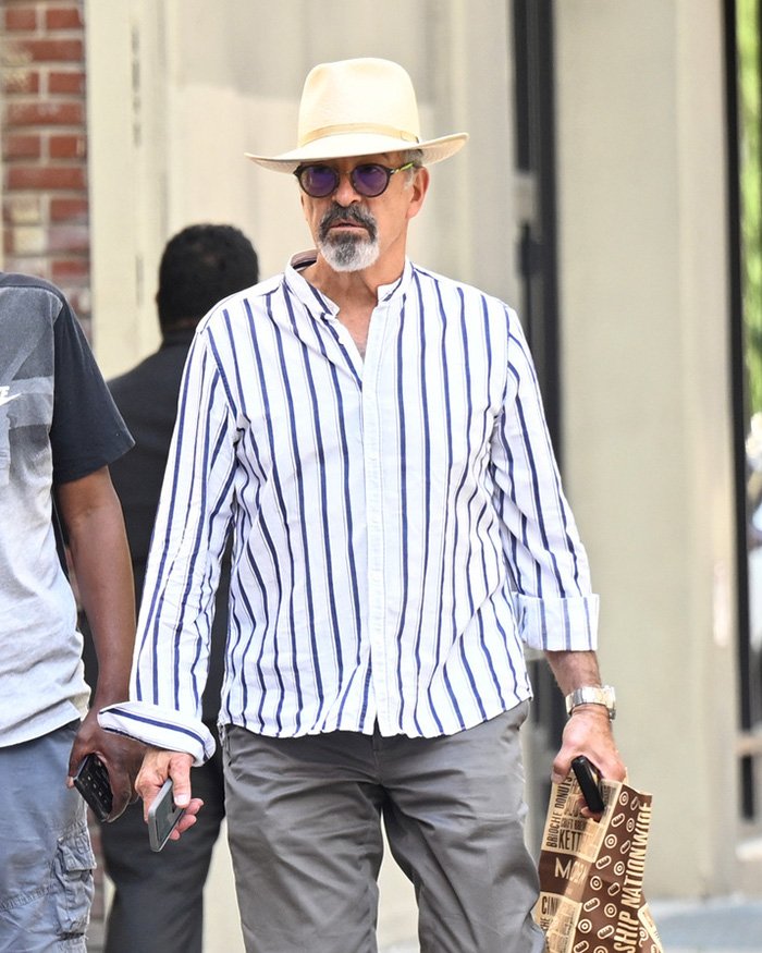 Man wearing a striped shirt and hat walking outdoors, related to Jeffrey Epstein’s brother final conversation topic.