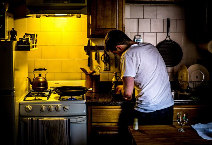 Man cooking alone in a dimly lit kitchen, symbolizing a man giving wife a second chance after she leaves.