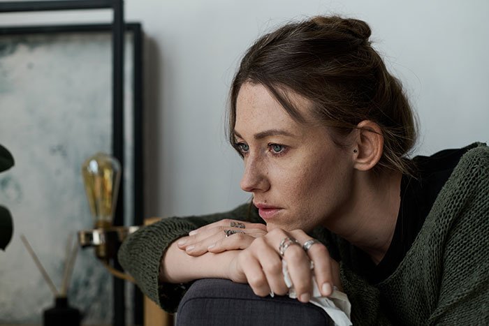 Woman looking distressed and thoughtful at home, reflecting on man's marriage on the rocks after learning about a 12-year-old daughter.