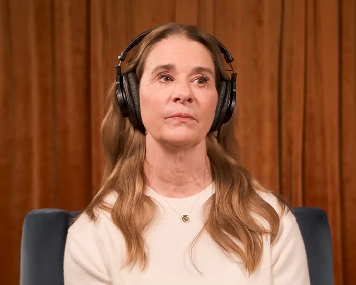 Melinda French Gates wearing headphones and a white top, looking thoughtful during a recorded interview session.