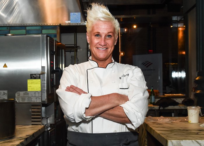Chef Anne Burrell standing in kitchen with arms crossed, related to police report unveiling alleged tragic passing details.