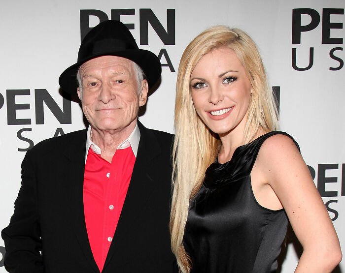 Hugh Hefner with widow standing side by side at a red carpet event, posing and smiling for the camera.