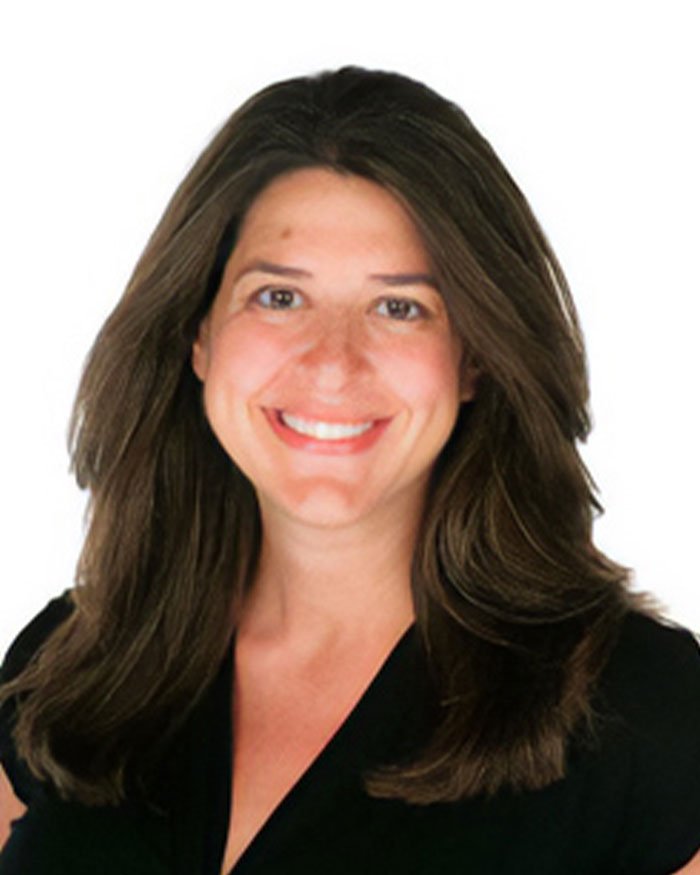 Smiling woman with long brown hair in black top, representing teacher's hot-mic moment sparking outrage among students.