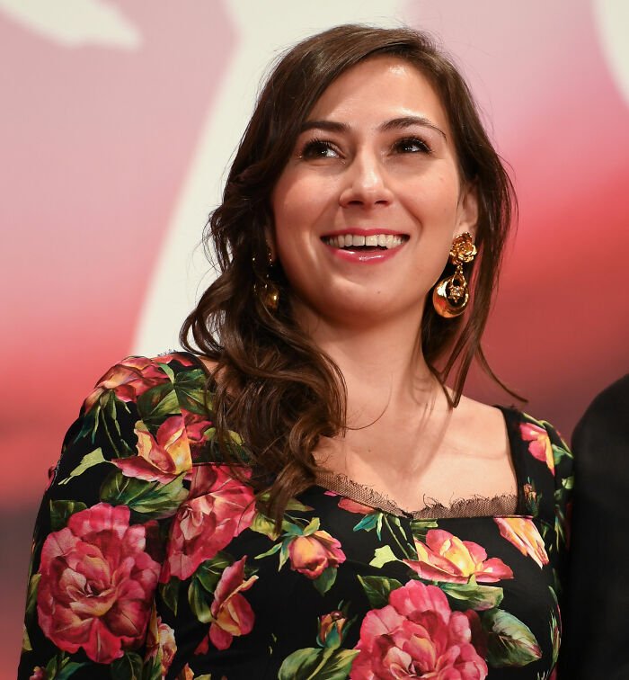 Smiling woman with floral dress and gold earrings photographed at an event discussing Tommy Lee Jones daughter’s cause of passing.