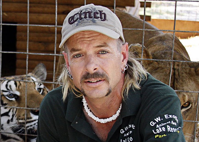 Joe Exotic with animals behind a cage in a park, posting about Epstein files breaking the internet buzz.