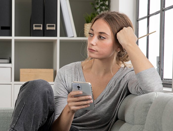 Woman looking tired and frustrated while holding a phone, reflecting fatigue from friend’s strict diet enforcement.