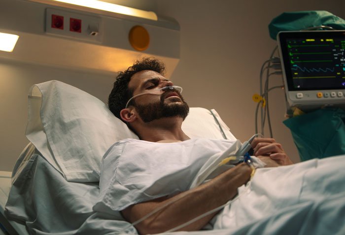 Man lying in hospital bed with oxygen tube, representing woman realizing her late brother’s baby isn’t his after testing.