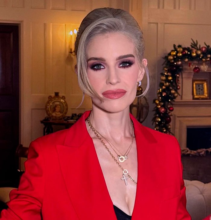 Kelly Osbourne wearing a red blazer and layered necklaces with bold makeup as fans discuss buccal fat removal rumors.