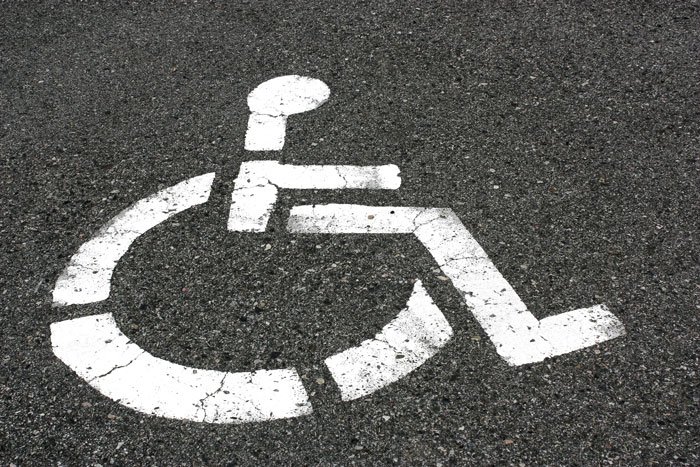 Handicapped parking spot symbol painted on asphalt, representing accessibility and challenges in parking drama situations.