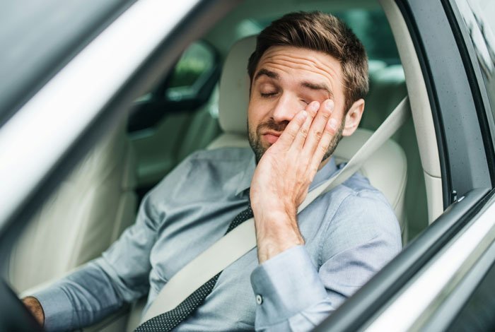 Man in a car rubbing his eyes, showing frustration after dealing with handicapped spot drama and confrontation.